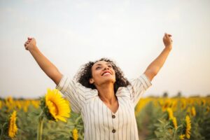 A woman victoriously punching the air in a sunflower field
